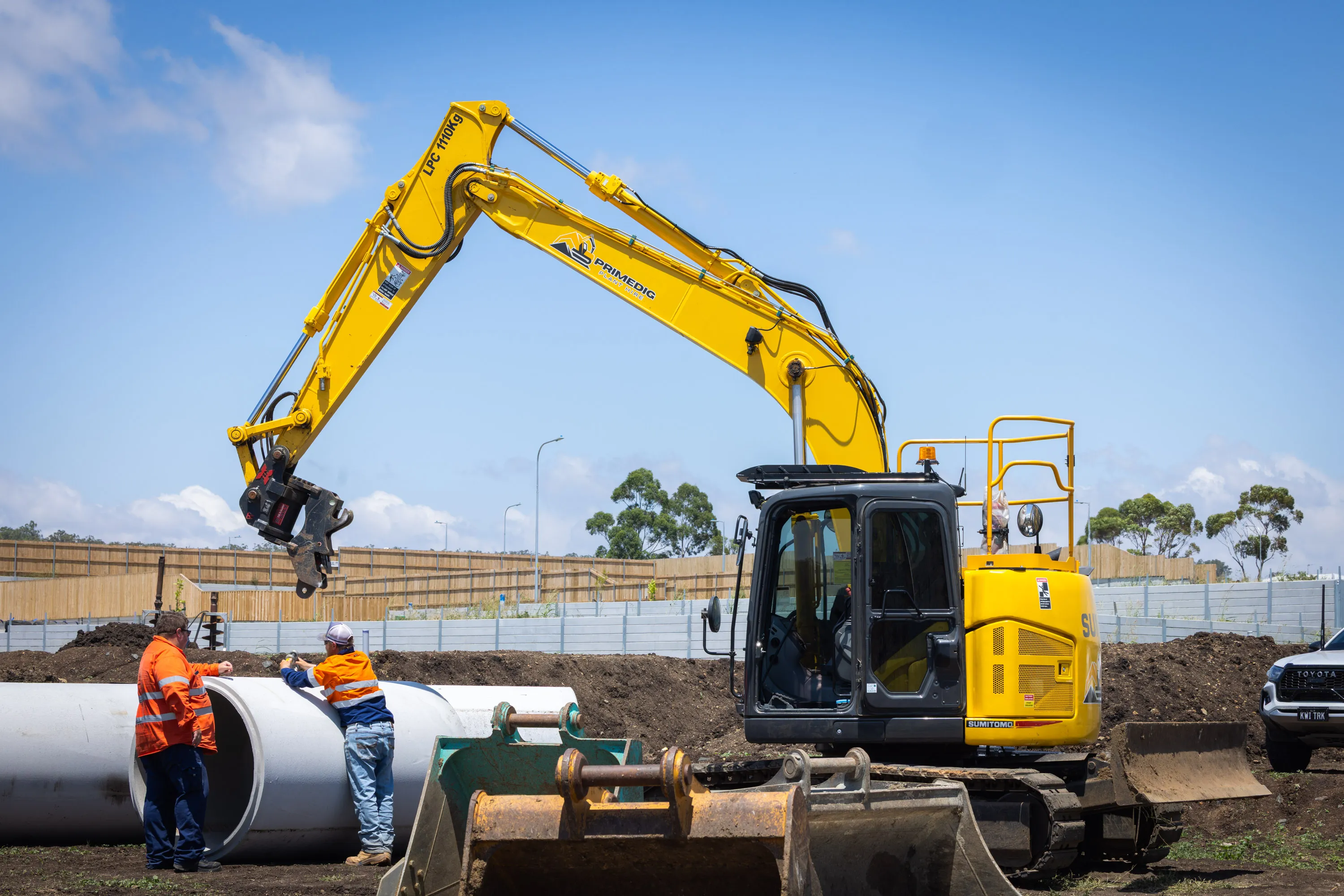 PrimeDig excavator and site crew laying a stormwater pipe on a civil project